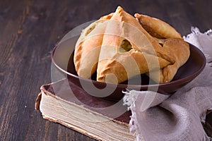 Homemade pies with potatoes and onions in a ceramic bowl on old cookbook