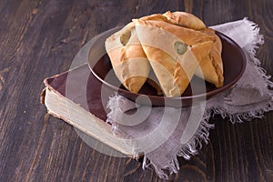 Homemade pies with potatoes and onions in a ceramic bowl on old cookbook