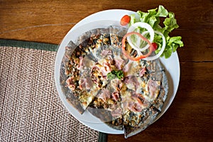 Homemade Pizza ham cheese with charcoal dough decorated with fresh vegetables.