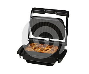 Homemade pizza with salami, bacon, tomato sauce, yellow cheese and mozzarella in a black electric grill in a baking dish.