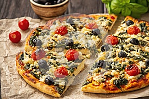 Homemade pizza with spinach, tomatoes and olives