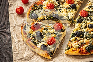 Homemade pizza with spinach, tomatoes and olives