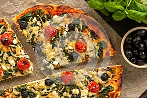 Homemade pizza with spinach, tomatoes and olives