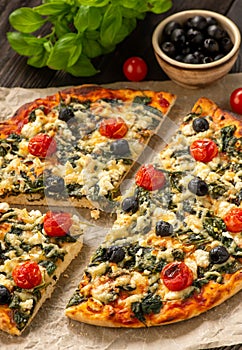 Homemade pizza with spinach, tomatoes and olives