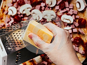 Homemade pizza step by step instruction.DIY pizza step 6.cooking, food and home concept - close up of female hands grating cheese