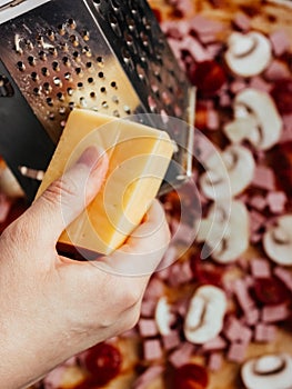 Homemade pizza step by step instruction.DIY pizza step 6.cooking, food and home concept - close up of female hands grating cheese