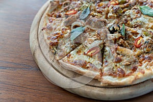 Homemade pizza with tomatoes, olives, salami, mozzarella cheese and seafoog on wooden rustic table