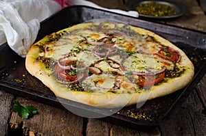 Homemade pizza with zaatar, tomatoes, onion and cheese on wooden background. Eastern cuisine. Selective focus