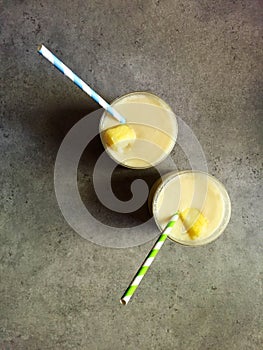 Homemade piÃ±a colada in two glasses with striped paper straws