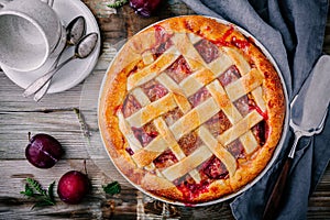 Homemade plum pie on rustic background