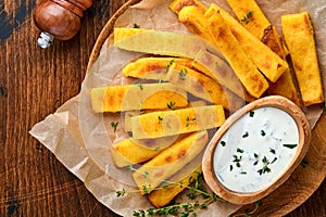 Homemade polenta chips fries with sea salt, parmesan, thyme, rosemary with yogurt sauce. Typical Italian fried polenta. Fried corn