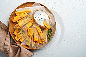 Homemade polenta chips fries with sea salt, parmesan, thyme, rosemary with yogurt sauce. Typical Italian fried polenta. Fried corn