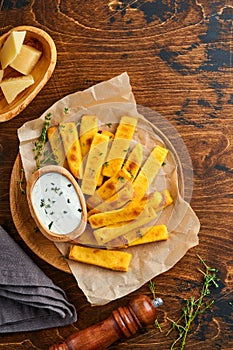 Homemade polenta chips fries with sea salt, parmesan, thyme, rosemary with yogurt sauce. Typical Italian fried polenta. Fried corn