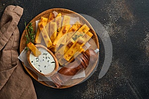 Homemade polenta chips fries with sea salt, parmesan, thyme, rosemary with yogurt sauce. Typical Italian fried polenta. Fried corn