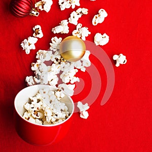 Homemade popcorn for a festive treat in red Christmas mugs with shiny New Year's red and gold Christmas decorations