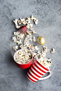 Homemade popcorn for a festive treat in red Christmas mugs with shiny New Year's red and gold Christmas decorations