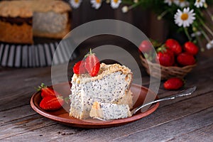 Homemade poppy seed cheese cake in a ceramic plate on an wooden background with flowers and strawberries on a background