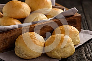 Homemade potato bread rolls on wooden tray.