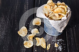 Homemade potato chips over dark wooden background