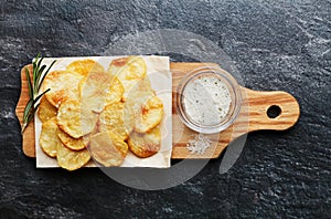 Homemade potato chips with sea salt and herb on cutting board