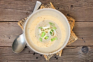 Homemade potato and leek soup, top view on rustic wood