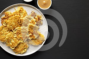 Homemade Potato Pancakes Latkes with Apple Sauce and Sour Cream on a black wooden background, top view. Flat lay, overhead, from
