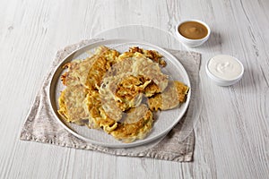 Homemade Potato Pancakes Latkes with Apple Sauce and Sour Cream on a white wooden background, low angle view