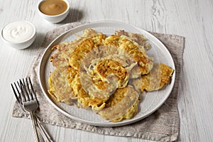 Homemade Potato Pancakes Latkes with Apple Sauce and Sour Cream on a white wooden background, side view