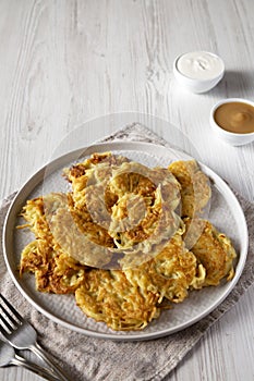 Homemade Potato Pancakes Latkes with Apple Sauce and Sour Cream on a white wooden background, side view. Space for text