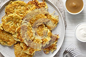 Homemade Potato Pancakes Latkes with Apple Sauce and Sour Cream on a white wooden background, top view. Flat lay, overhead, from