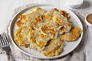 Homemade Potato Pancakes Latkes with Apple Sauce and Sour Cream on a white wooden surface, side view. Close-up