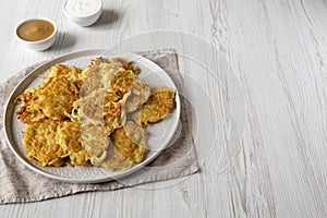 Homemade Potato Pancakes Latkes with Apple Sauce and Sour Cream on a white wooden surface, side view. Copy space