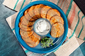 Homemade potato pancakes, latkes, draniki, hash browns, fritters served with sour cream and sunflower sprouts. Top view