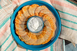 Homemade potato pancakes, latkes, draniki, hash browns or fritters served with sour cream. Top view. Closeup