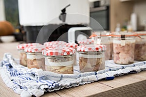 Homemade pressure canned meat as Russian specialty Tuschonka in glass jars on towel and domestic kitchen electrical preserver