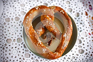 Homemade pretzel on a bowl of chickpea soup with walnuts