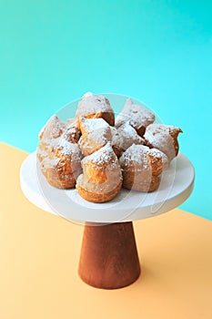 Homemade profiteroles with powdered sugar. Cream puffs filled vanilla custard and dusted with icing on a bright background.