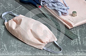 Homemade protective mask and pieces of cloth on a gray background