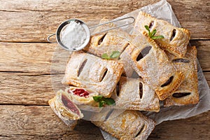 Homemade puff pastry berry pies with powdered sugar and mint close-up. Horizontal top view