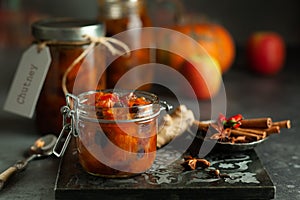 Homemade pumpkin and apple chutney with raisins in jars on a table. Delicious sweet spicy sauce preserved for autumn and winter