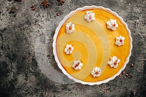Homemade pumpkin cheesecake with caramel sauce and seeds on top on metal wicker stand