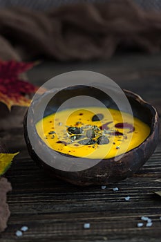 Homemade pumpkin cream soup with pumpkin seeds and pumpkin oil on a dark background. Rustic style