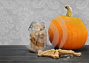 Homemade pumpkin dog cookie bones in a canning jar next to a pumpkin.