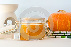 Homemade pumpkin face mask in a small white bowl and make-up brush. Natural autumn beauty treatment and spa recipe.