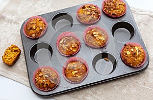 Homemade pumpkin muffins with pumpkin seeds and walnut pieces. Fall baking for Thanksgiving and Halloween. Cupcakes in baking dish