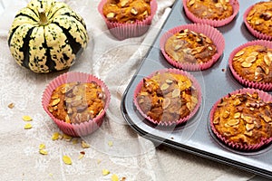 Homemade pumpkin muffins with pumpkin seeds and walnut pieces. Fall baking for Thanksgiving and Halloween. Cupcakes in baking dish