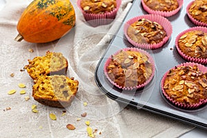 Homemade pumpkin muffins with pumpkin seeds and walnut pieces. Fall baking for Thanksgiving and Halloween. Cupcakes in baking dish