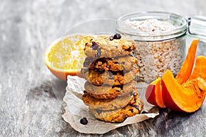 Homemade pumpkin and orange cookies on rustic wooden background