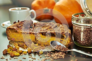 Homemade pumpkin pie with raisins, linseeds and flax flour on wooden table with cup of coffee and pumpkins