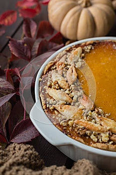 Homemade pumpkin pie with walnuts, beautifully decorated with dough leaves, dark wooden background